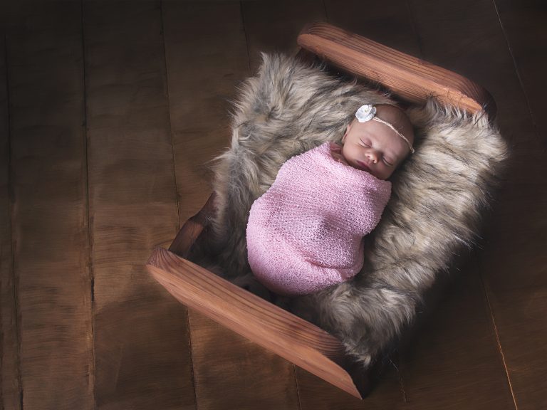 tiny baby in wooden bed