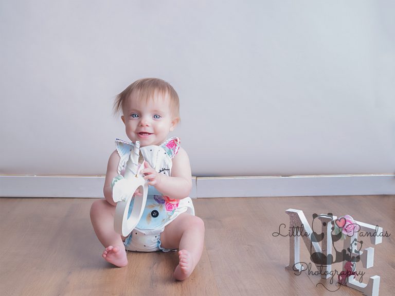 Little girl in unicorn romper holding letter O