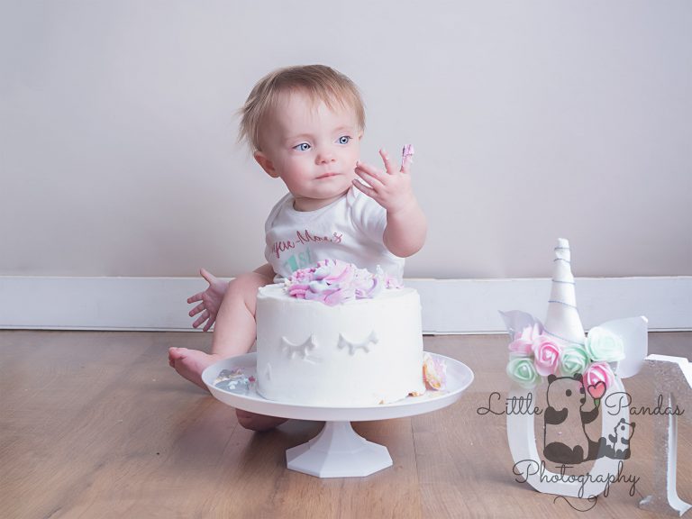 Little girl cake smash cake on fingers