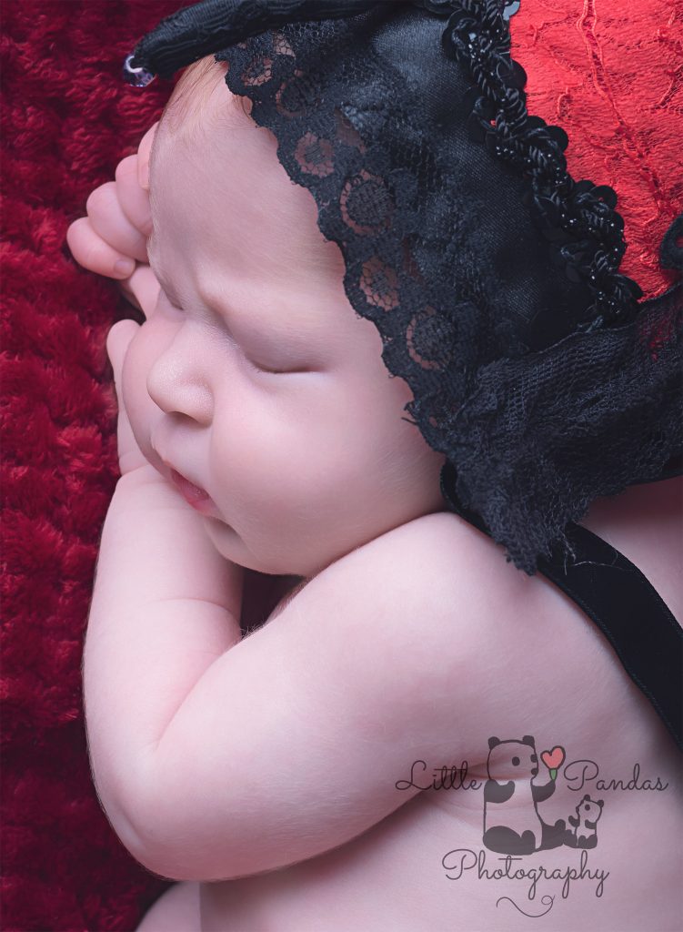 Baby girl in ladybird bonnet on red background