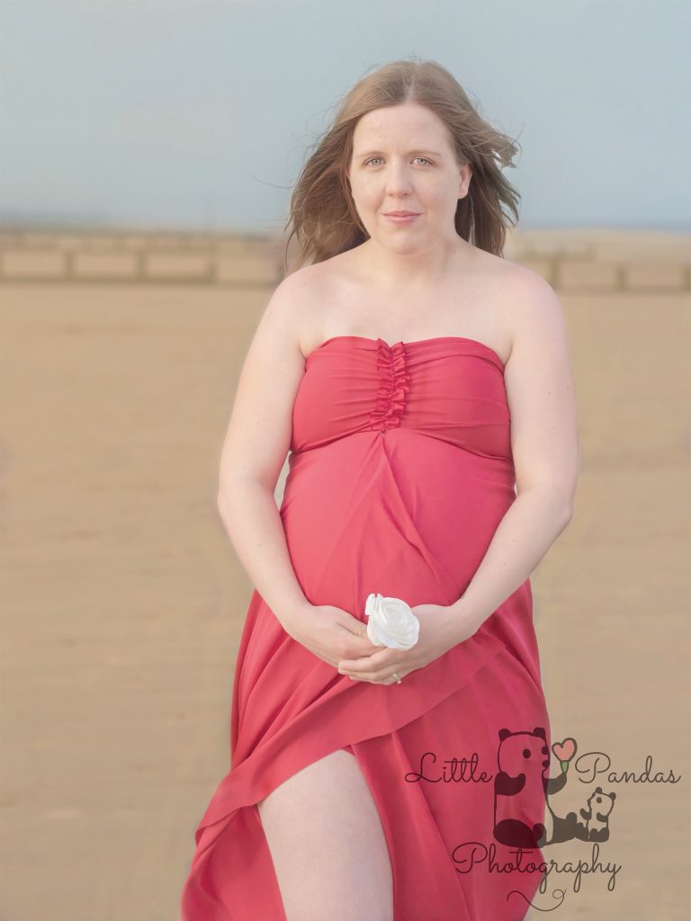 Pregnant lady in red dress on the beach