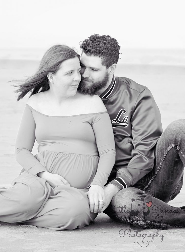 Black and white couple on beach pregnant