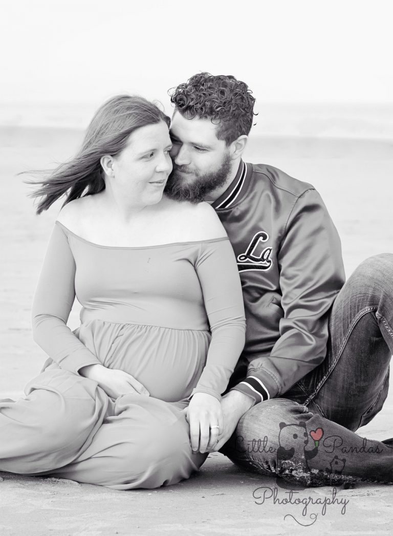 Black and white couple on beach pregnant