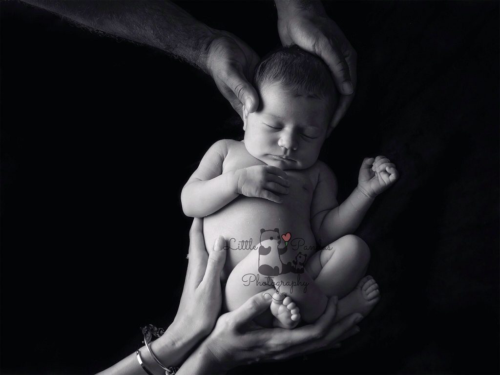 Newborn photography black and white baby in parents' hands